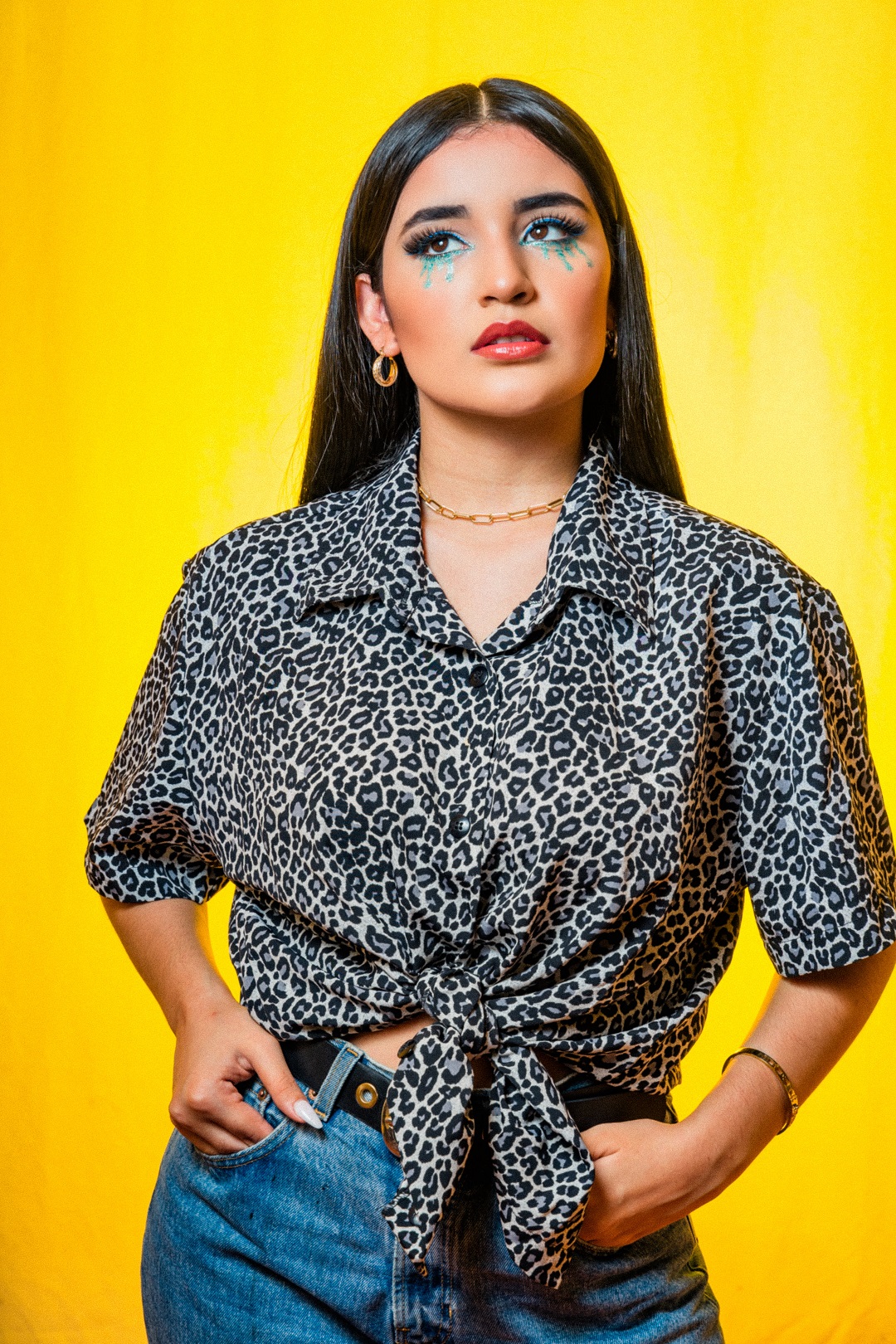 Mujer con cabello negro y blusa de leopardo posando